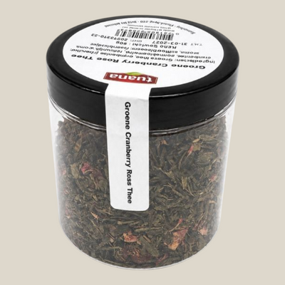 TuanaShop BV Groene Cranberry Rose Thee in een transparante pot met losse groene theeblaadjes, cranberry en rozen.