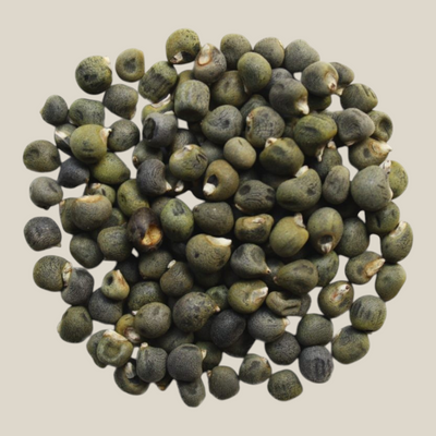 TuanaShop BV gedroogde okra zaden voor thee of consumptie, kleine ronde groene zaden op een witte achtergrond.