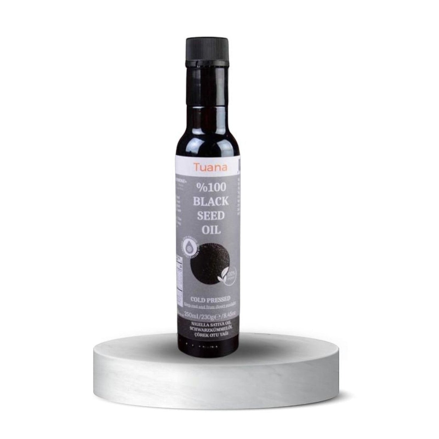 TuanaShop BV 100% biologische koudgeperste zwarte komijnzaadolie in een glazen fles van 250ml op een wit voetstuk.