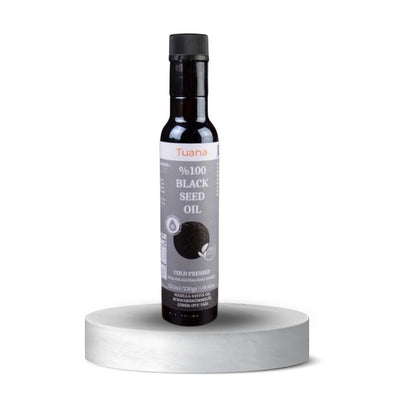 TuanaShop BV 100% biologische koudgeperste zwarte komijnzaadolie in een glazen fles van 250ml op een wit voetstuk.